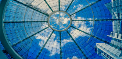 Glass ceiling with blue sky and white puffy clouds