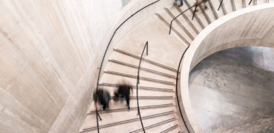 People walking down a curved white staircase