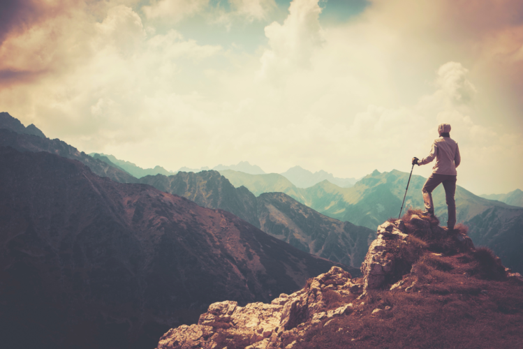 Woman standing on top of a mountain overlooking the sky