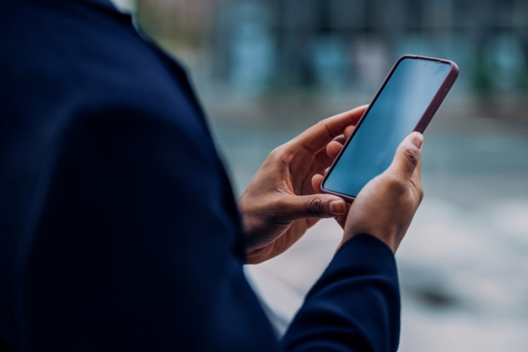Business professional using a cell phone, representing TCPA regulatory updates and compliance challenges discussed by DTO attorneys.